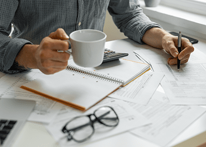 Person filling out paperwork on crowded desk