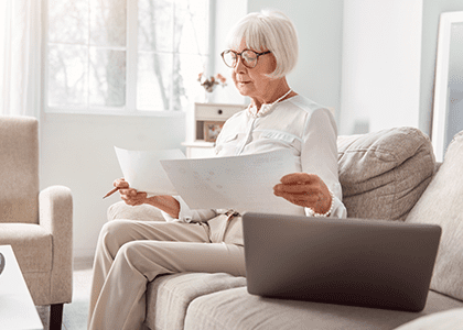 Mature woman looking at papers from her couch