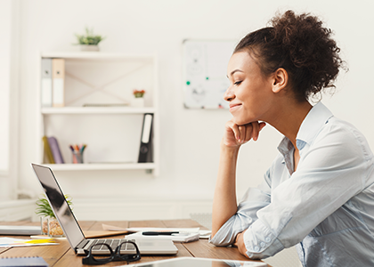 Woman smiling at her laptop in a home office setting